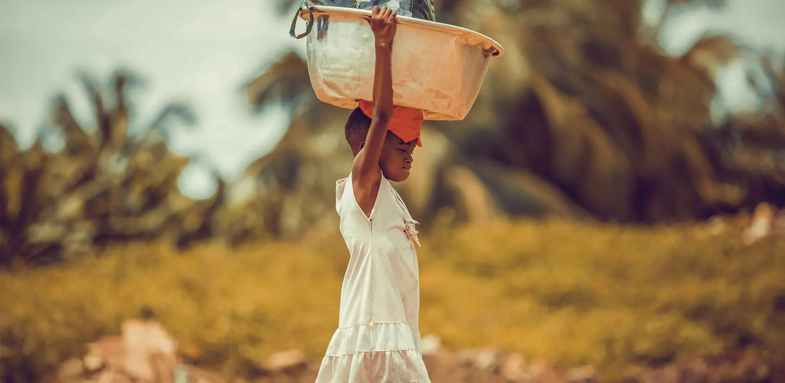 A young girl carrying water on her head.