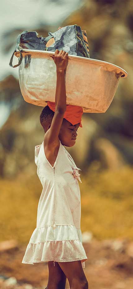 A young kayaye carries her bowl of washing to the river