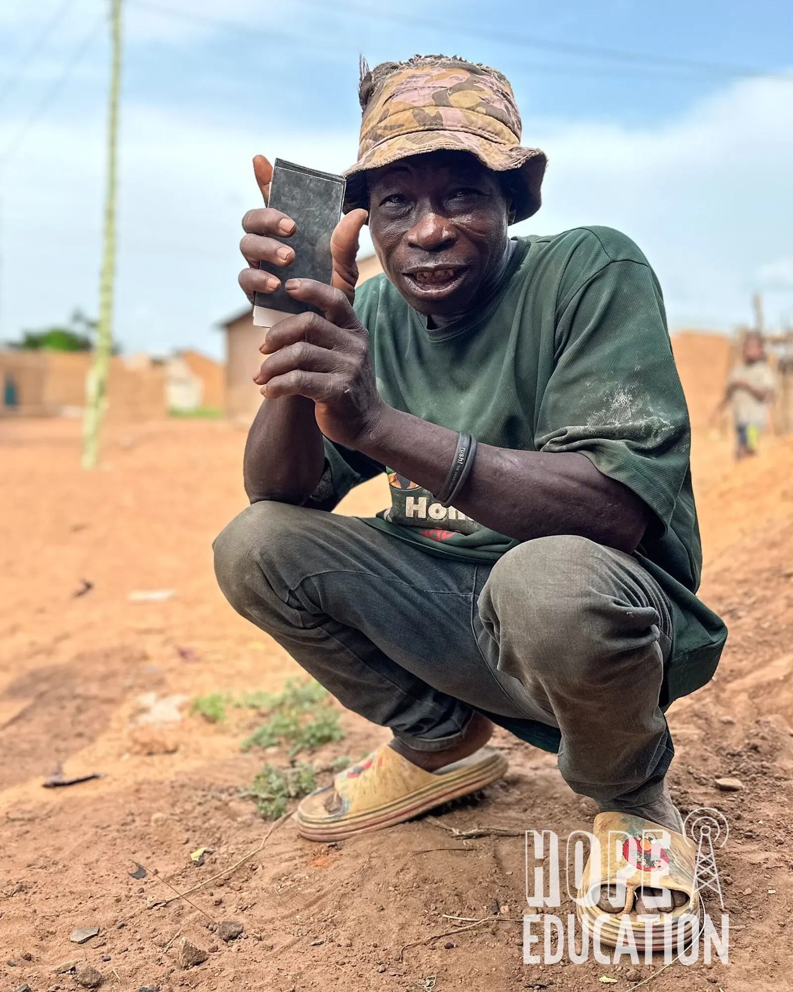 An unemployed former farmer in northern Ghana holding a broken smart phone