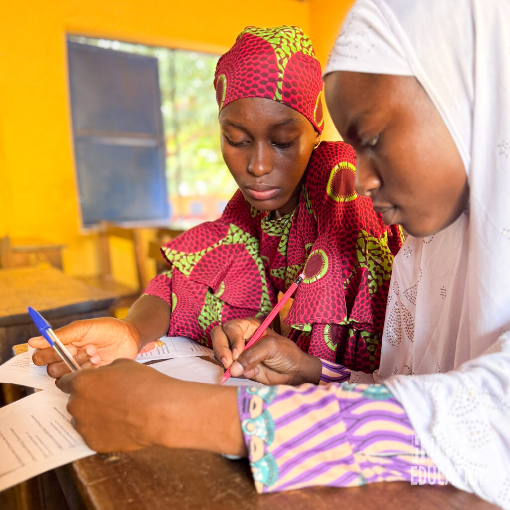 A Hope Education project volunteer supports a participant at a human trafficking community event with the monitoring and evaluation questionnaire