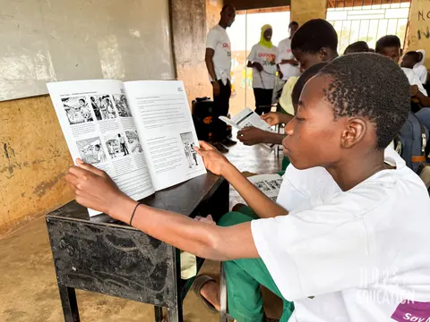 Students at Darrul Haddis Junior High School, Tamale reading the HEP human trafficking education program handout, filled with cartoons, quizzes, facts and revision notes.