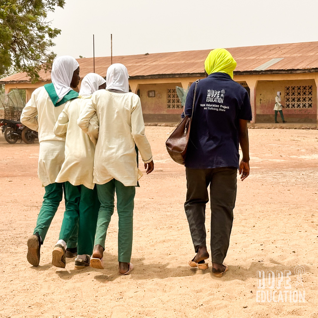 Programs Manager Mariama Adam walks to Darrul Haddis Junior High School, Tamale with three students